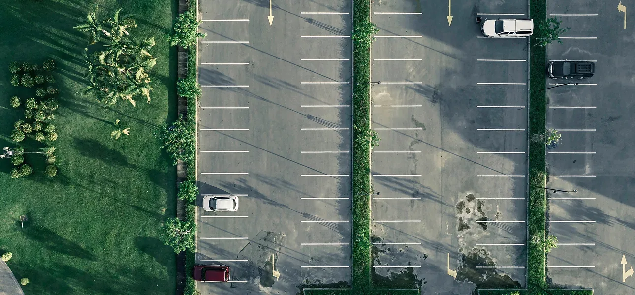 Aerial view of a parking lot with tree-lined islands evaluated for a solar carport