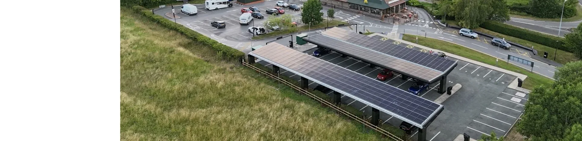 Aerial view of two solar carport rows covering a commercial parking lot next to a road