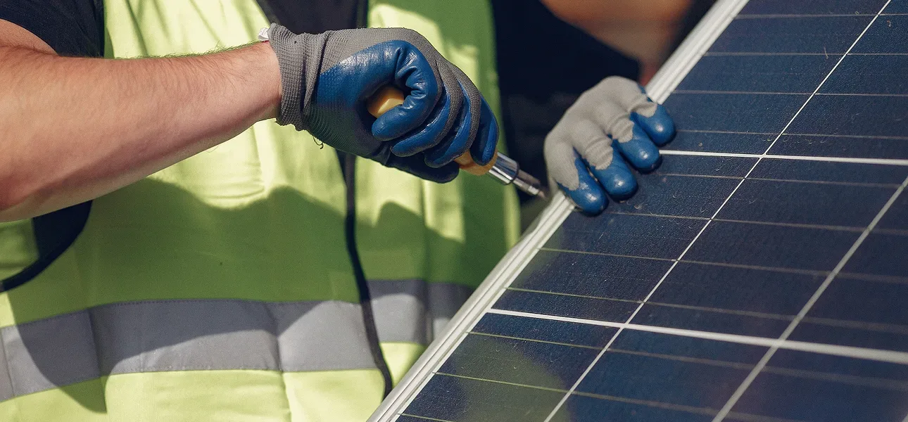 Installer in gloves and a safety vest mounting a solar panel