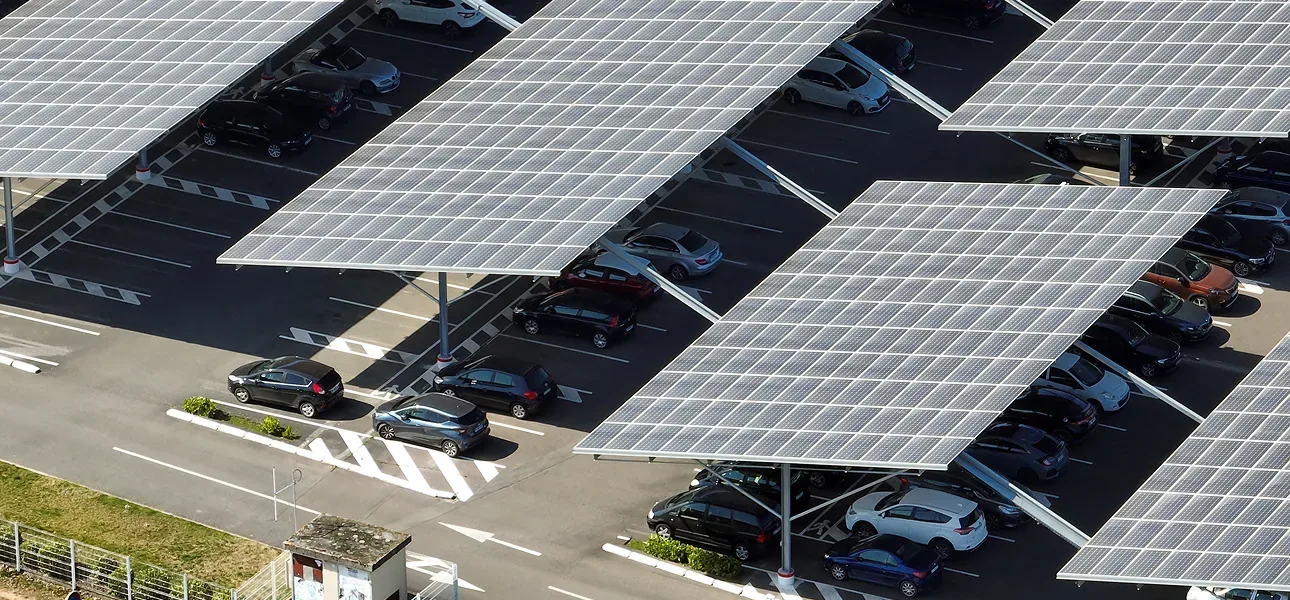 Aerial view of operating solar carports shading cars in a commercial parking lot